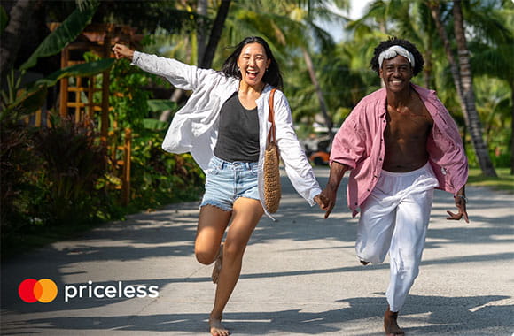 Two people running and laughing in a tropical location with priceless logo