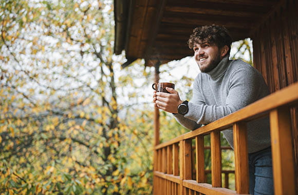 Person looking over porch with mug in hand