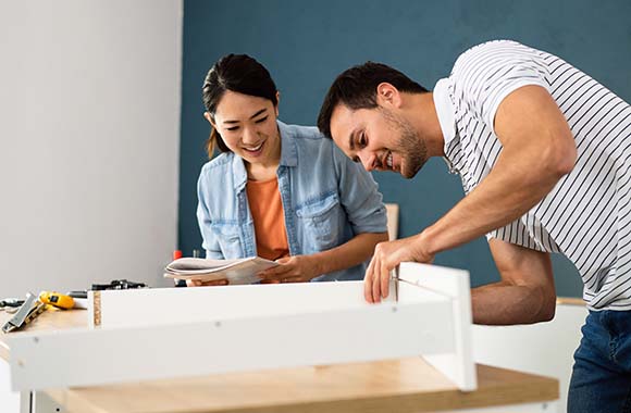 Two people putting together furniture