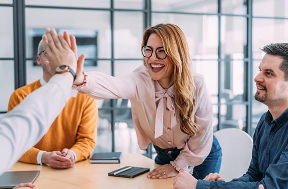 Two people high fiving in office