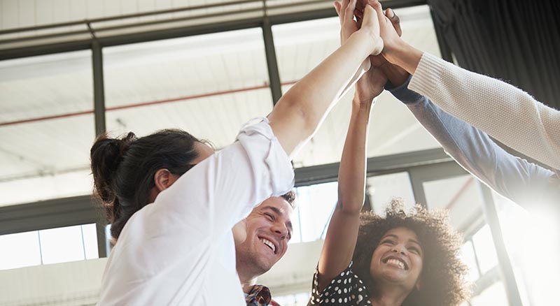 Group of colleagues high fiving in the air
