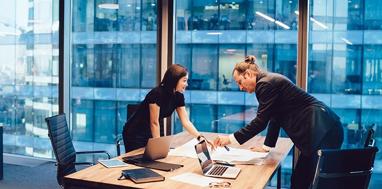 Two colleagues in workspace pointing at papers
