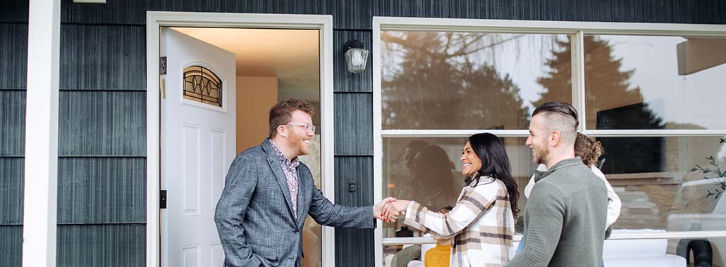 Person shaking hands with another person outside a home
