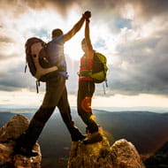 Man and woman high five after climbing to the top of the mountain