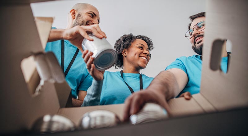 Volunteers placing canned food in a box