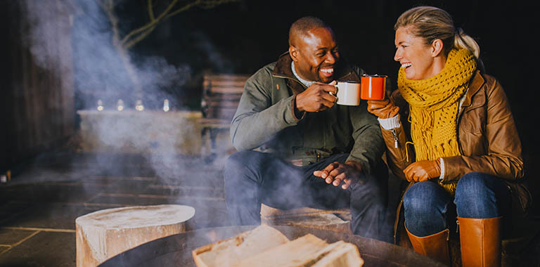 Two people cheering at a campfire