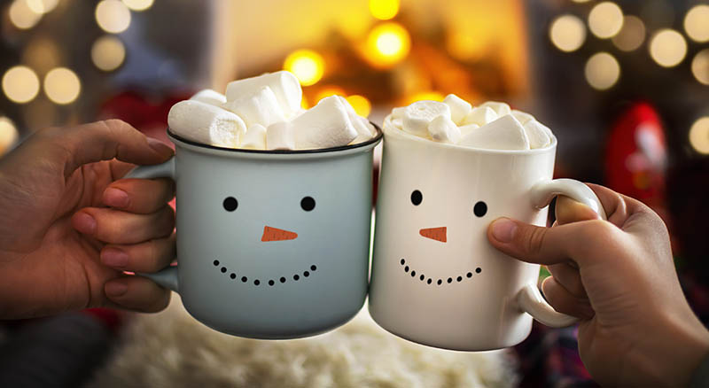 Two mugs with snowman and marshmallows cheering