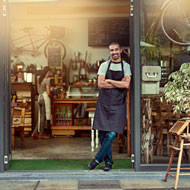 Man leans against open door of his bike shop