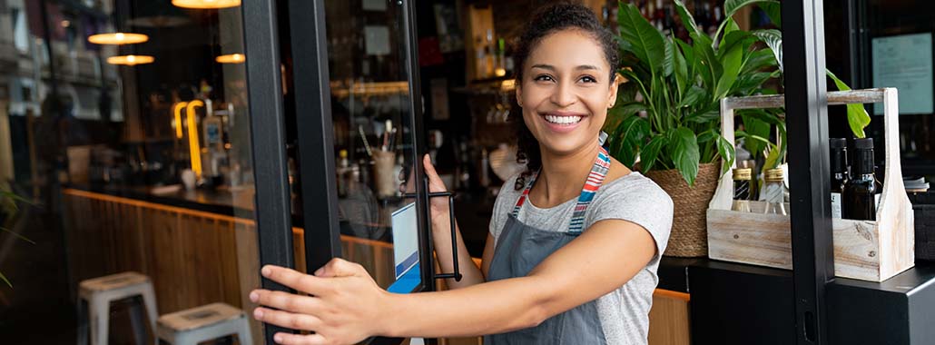 Person holding open a door to a business