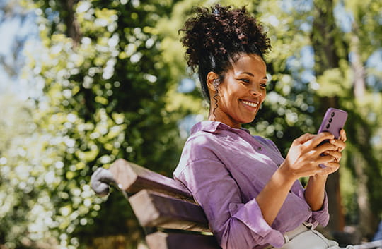 Person on a bench smiling while holding phone