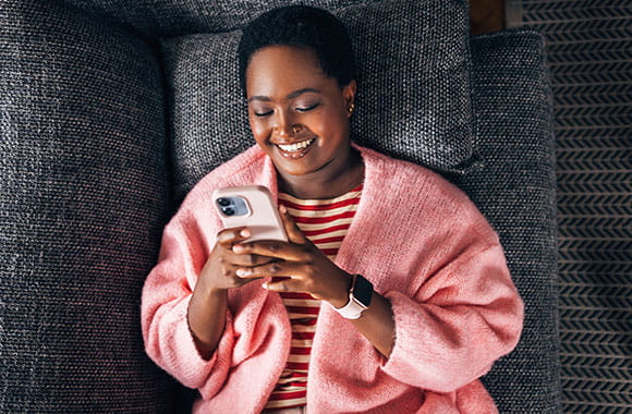 Person smiling while looking at phone on couch