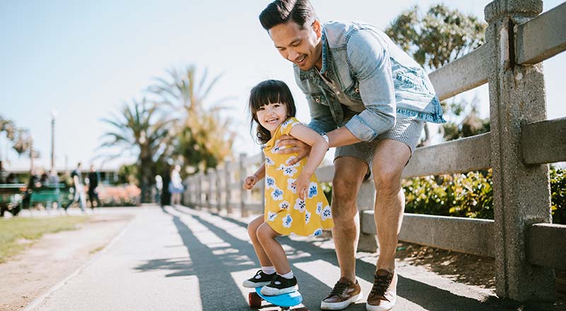 Father teaching child how to skateboard