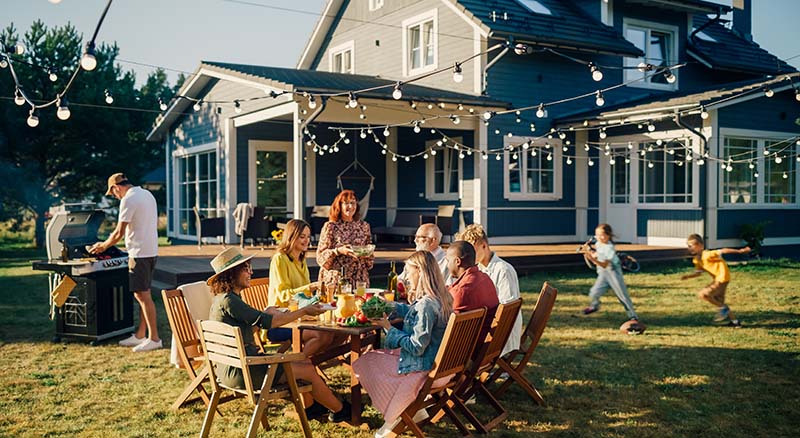 People having a dinner party in backyard while children run