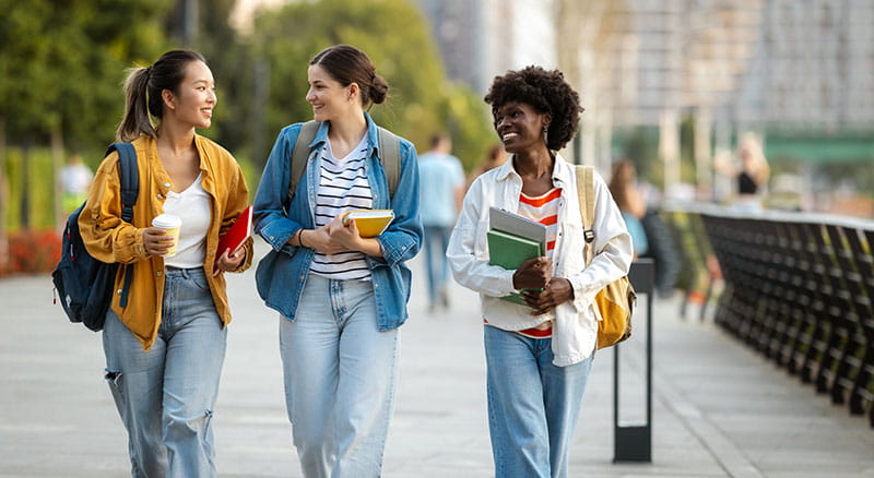 A group of students walking with books and smiling