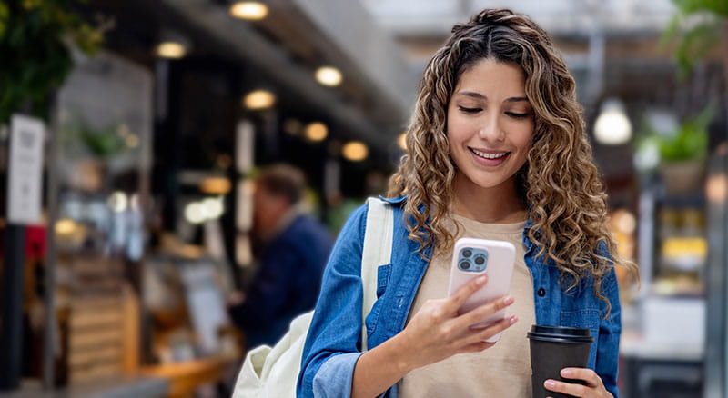 Person smiling and looking at phone outside