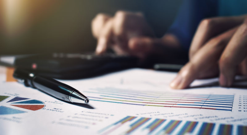 Close-up of person looking at financial spreadsheets and using a calculator