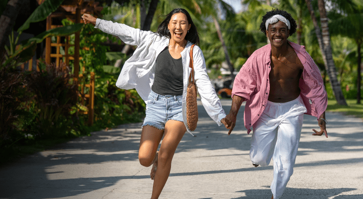 Two people holding hands and running in tropical location