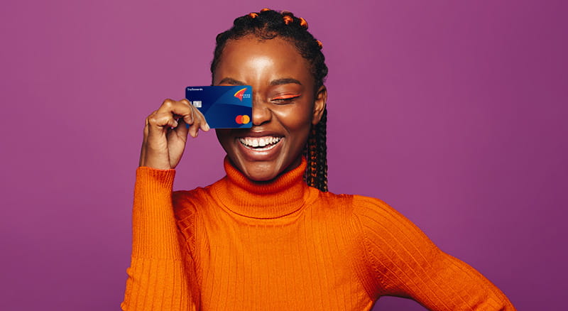 Person holding a TruRewards card up to face on a purple background