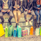 Young, hip group of friends sit around fountain with gift bags at their feet