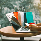 Woman at cafe table makes purchases online with her Banner Bank credit card with gift bags in the background