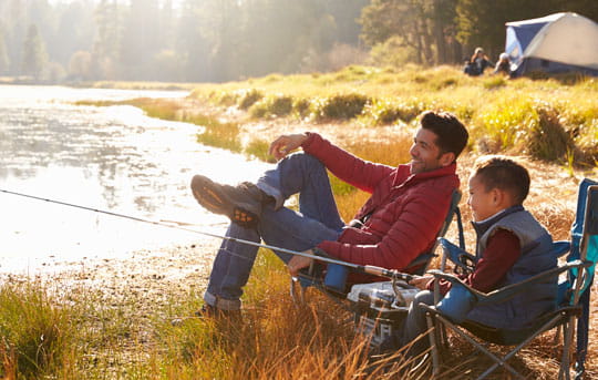 Father and son fish by a lake