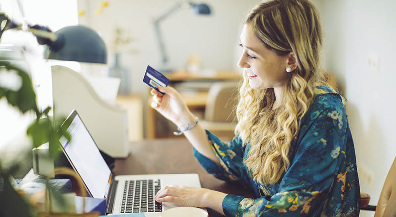 Person using laptop with Mastercard in hand