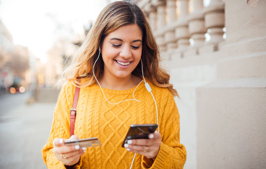 Woman shops on her phone with credit card