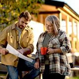 Person looking at plans while another holds coffee mug