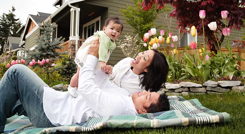 Parents laying in the front yard lifting up daughter