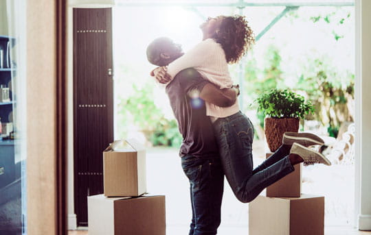 Young couple hug and celebrate after moving into their new home, financed by Banner Bank