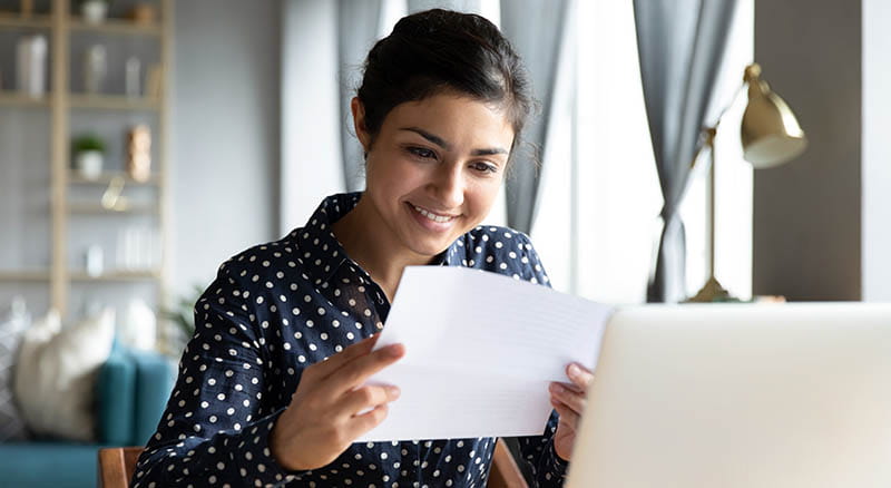 Woman looking at escrow statement and laptop