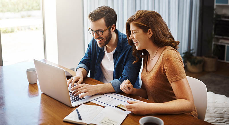 Couple looking at bills and laptop in house