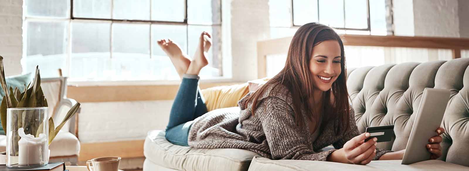 Woman using credit card on couch