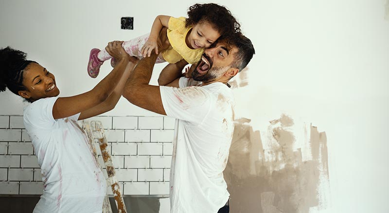 Couple playing with daughter while working on a home project