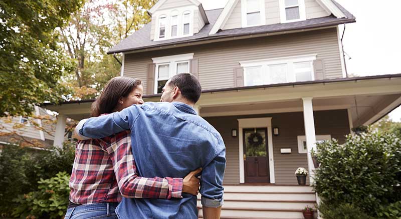 Two people hugging outside of a home