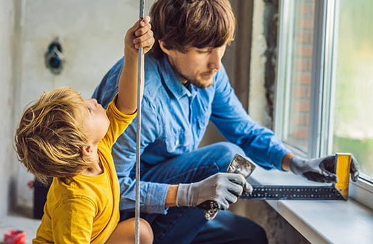 A father and child measure windows for renovations