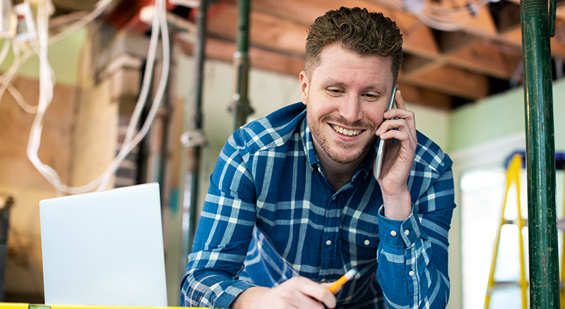 Person using loan by phone and computer in workshop