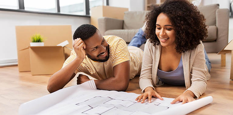 Couple looking at plans on the floor in a new home