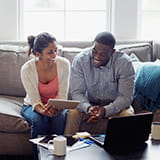 Couple looking at finances on tablet and laptop