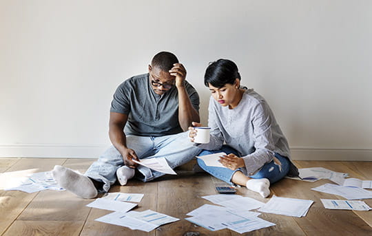 Couple looking at piles of bills on the floor