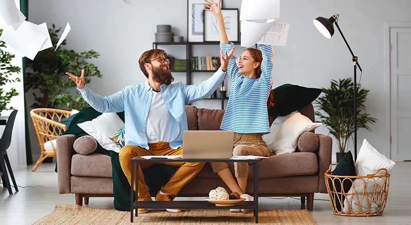 Couple throwing bills in the air at home