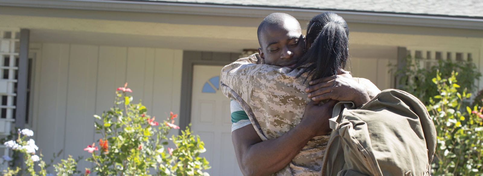 Man hugs woman, who is in military uniform