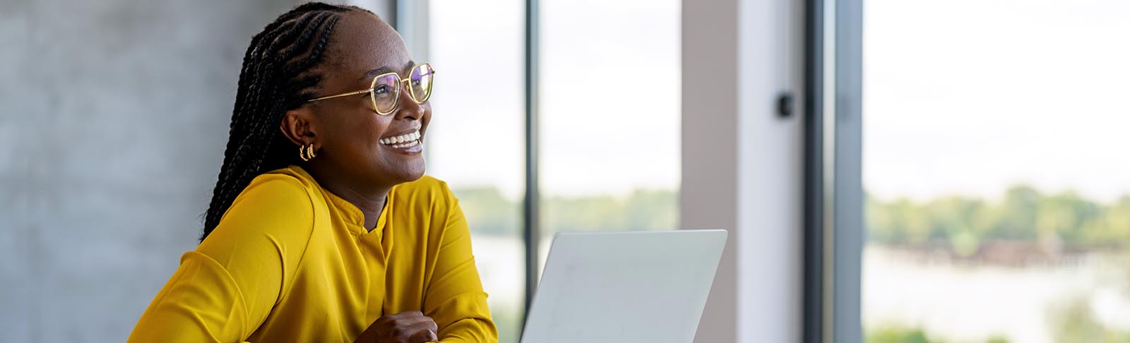 person at laptop smiling and looking into the distance