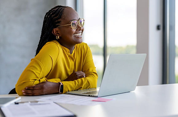 Person at laptop smiling into distance