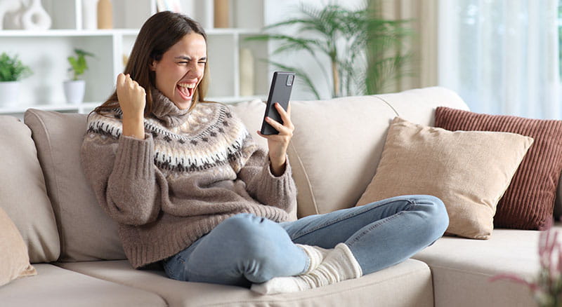 Happy person sitting on the couch looking at phone