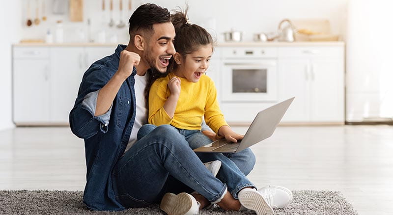Father and daughter excitedly looking at laptop