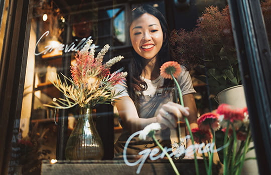 Person arranging flowers in a window display