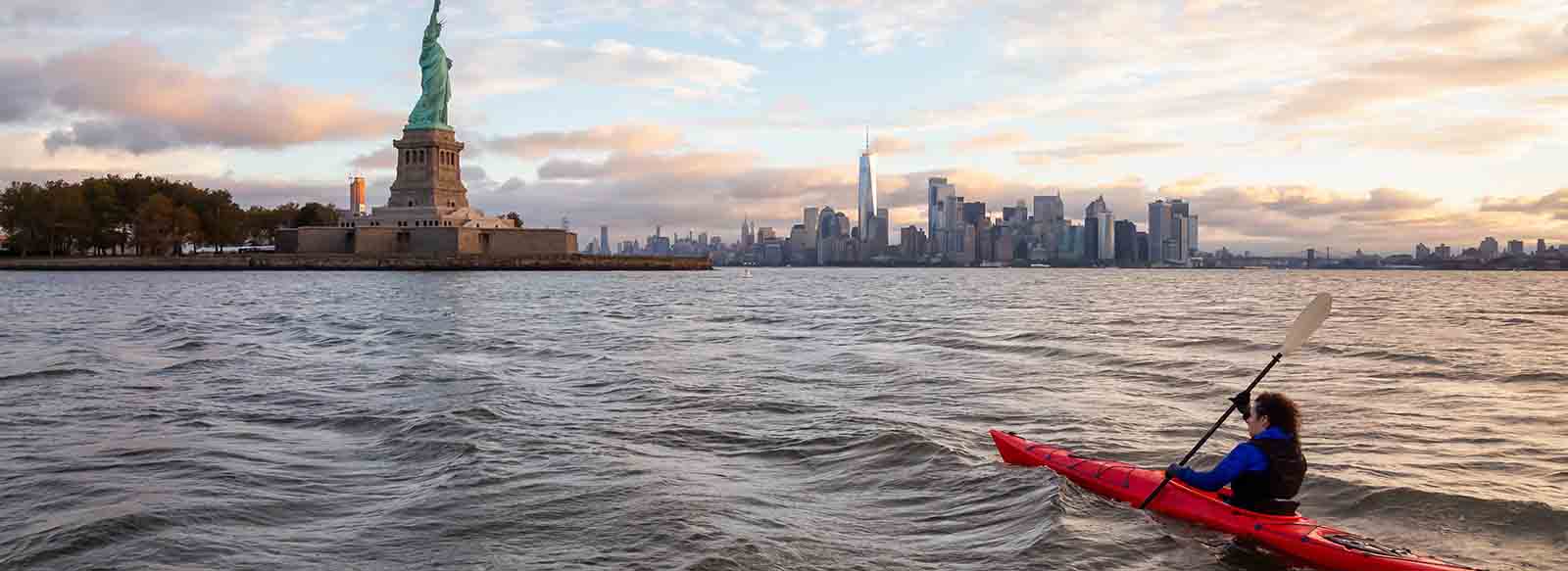 Person kayaking up to Statue of Liberty