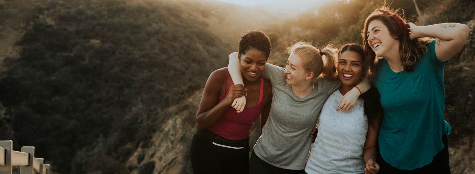 Four women hug while hiking