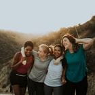 Four women hug while hiking